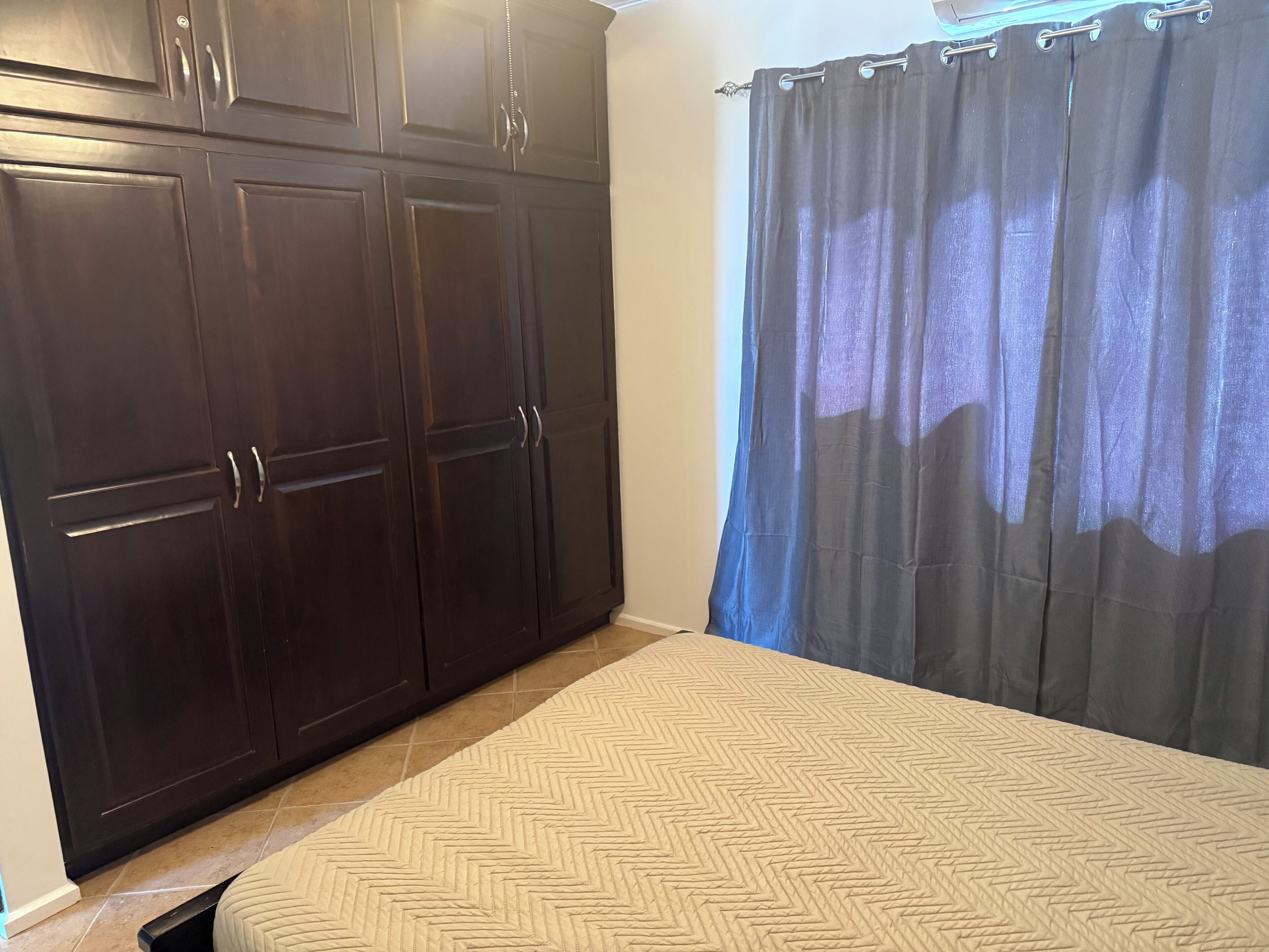 A bedroom with a bed, a wardrobe, and a curtain.