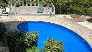 Una piscina con vista al océano, techo de tejas rojas y un edificio con varias ventanas.