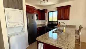 Una cocina con una isla central, horno empotrado, refrigerador y armarios de madera.