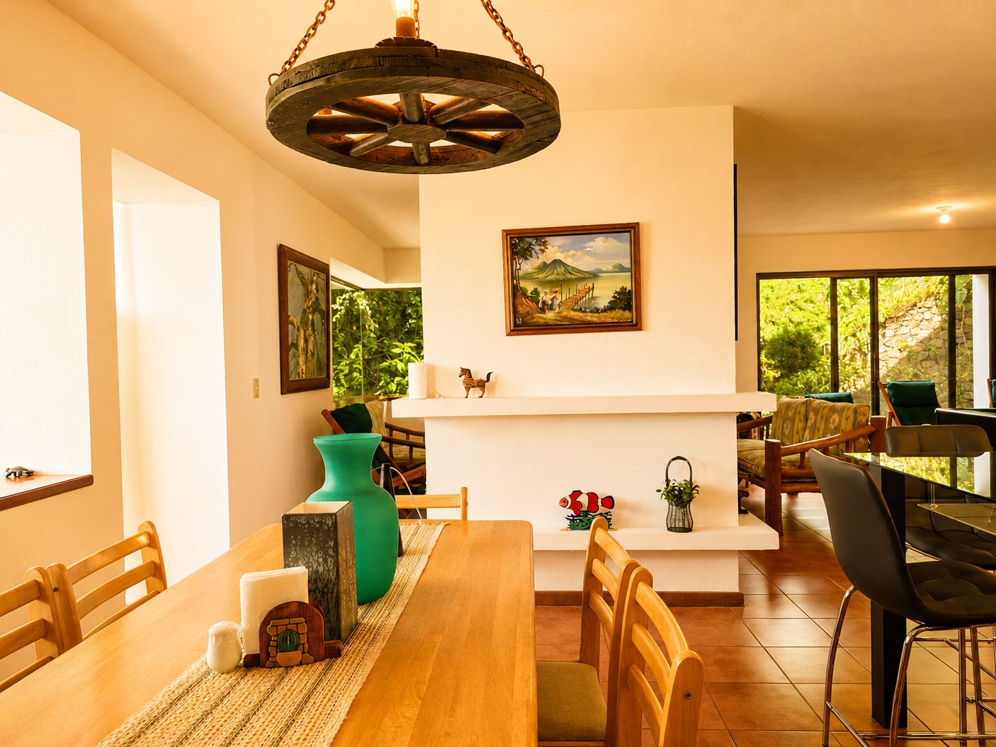 Un comedor con una mesa de madera, sillas, una lámpara colgante y un cuadro en la pared.