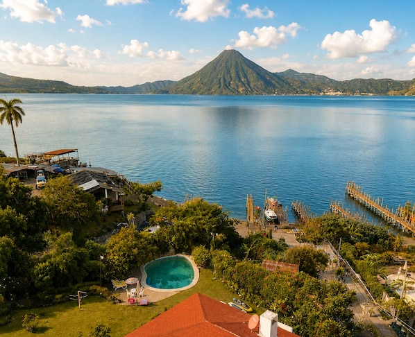 A tropical resort with a swimming pool, dock, and a mountain in the background.