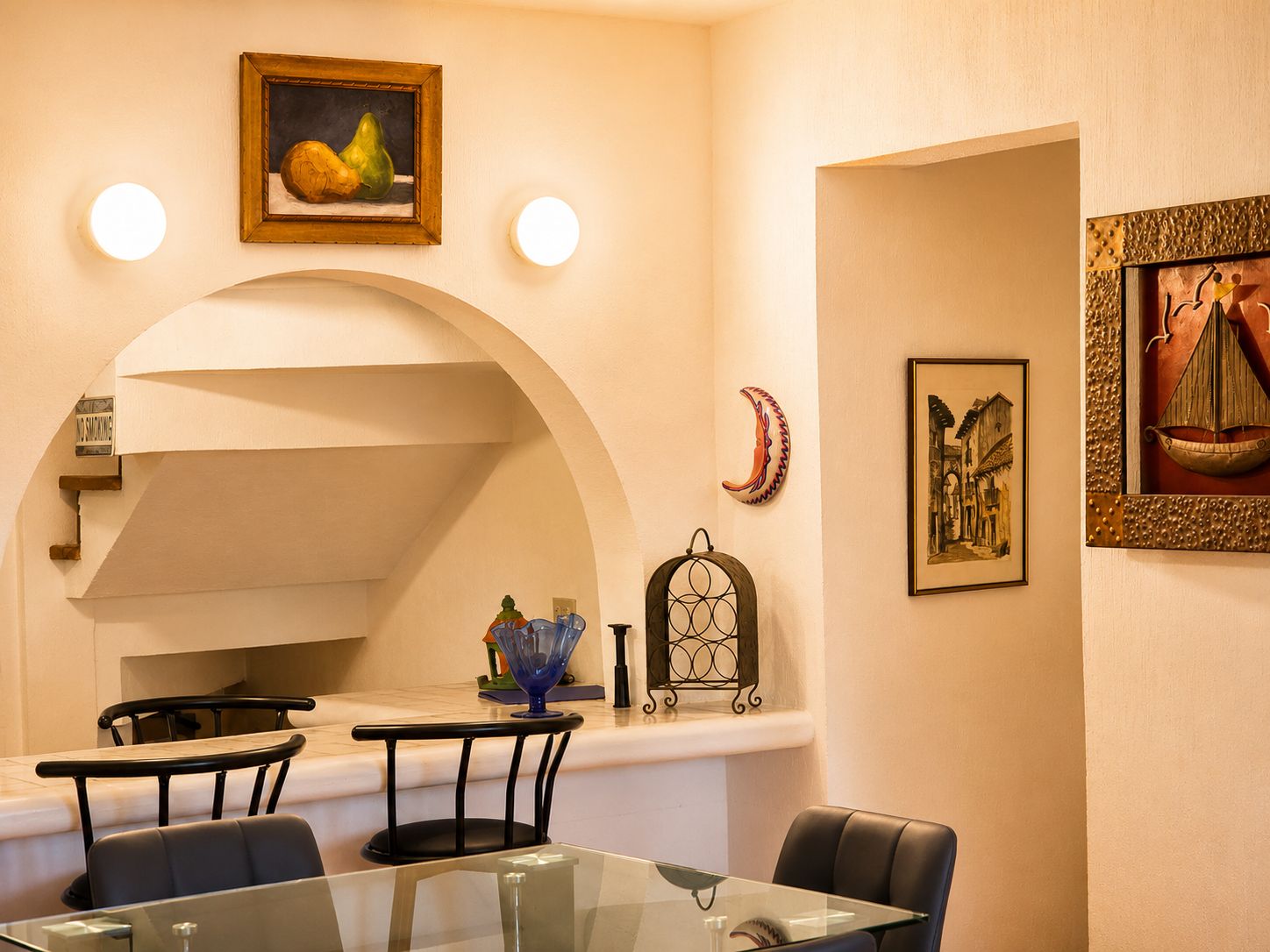 Un comedor con mesa de vidrio, sillas y un cuadro colgado en la pared.