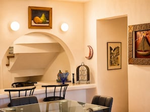 A dining area with a glass table, chairs, and a wall-mounted painting. - Casa Belen Lakefront Villa (Panajachel)
