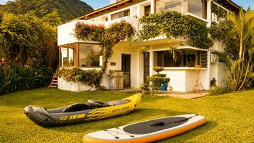 Una casa moderna con un césped cuidado, un kayak y una tabla de remo.