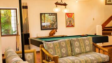Una sala de billar con mesa de pool, muebles de madera y una escalera.