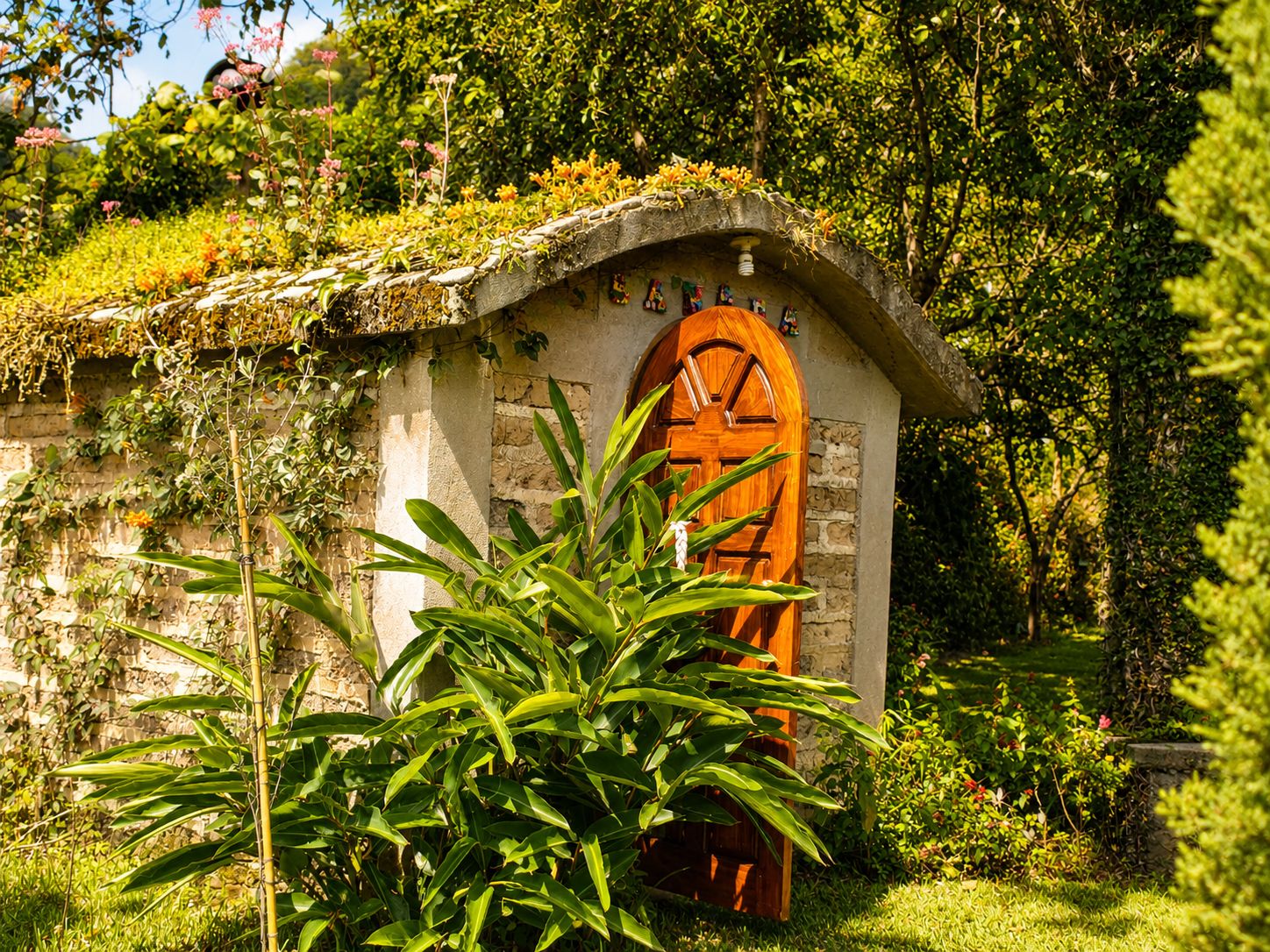 A small stone structure with a wooden door, surrounded by lush greenery.