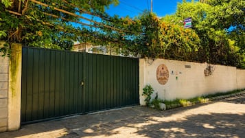 A gated entrance with a wall-mounted sign, a street lamp, and a paved pathway.