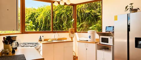 A modern kitchen with a large window, a sink, a stove, and a refrigerator.