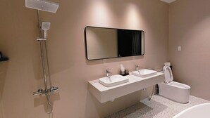 Een moderne badkamer met een douche, twee wasbakken, een toilet en een grote spiegel.