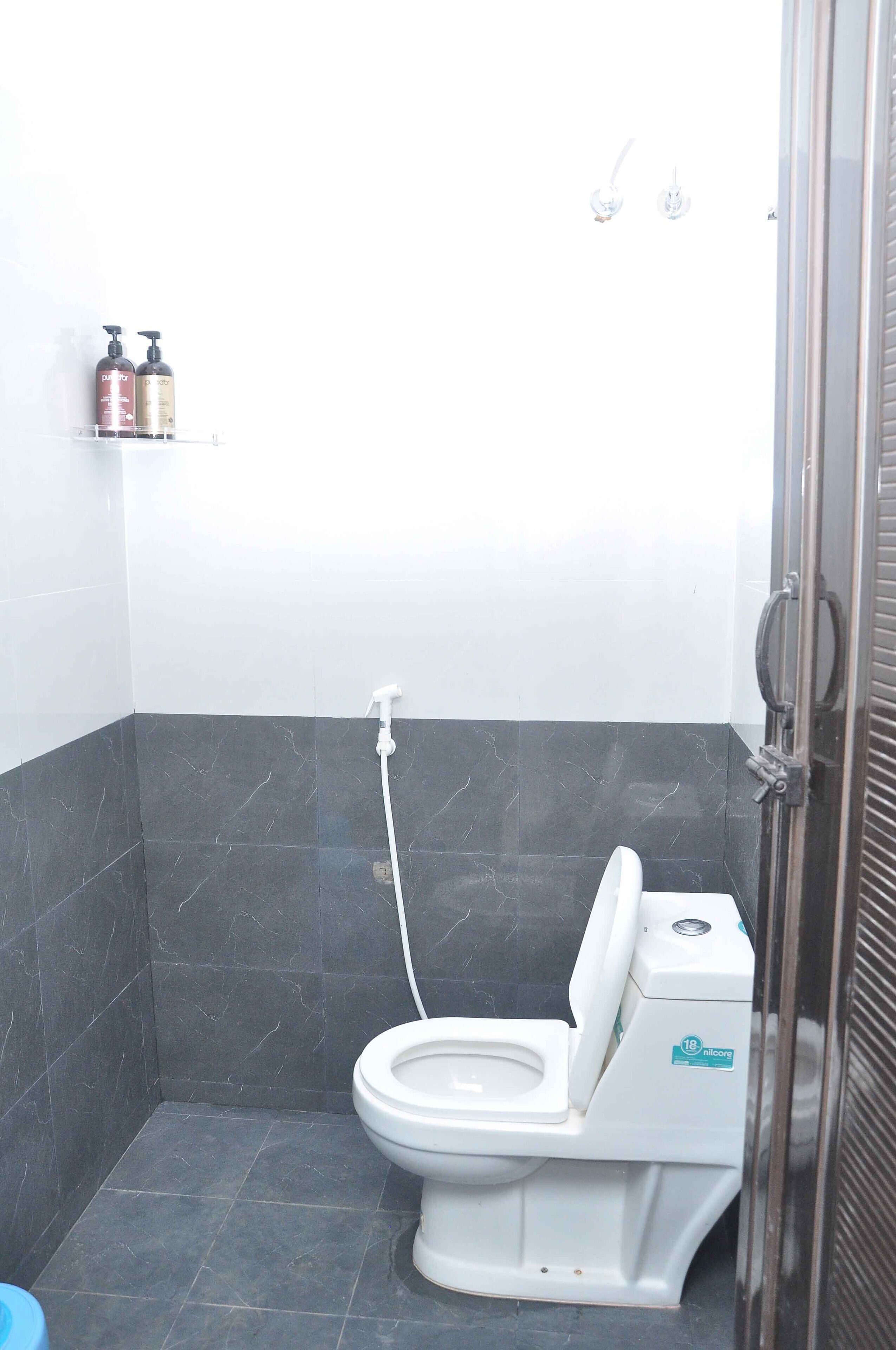 Ein Badezimmer mit Toilette, Dusche und einem Ablagefach für Toilettenartikel.