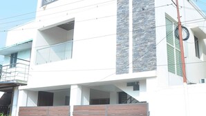 Un edificio moderno de dos plantas con fachada blanca, un muro de acento de piedra y una puerta de madera.