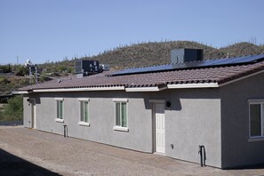 Un bâtiment doté d’un toit recouvert de tuiles, de panneaux solaires et d’une allée gravillonnée.