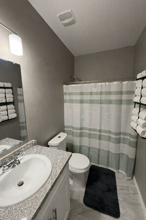 Une salle de bain avec un lavabo, des toilettes et un rideau de douche.