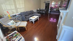 Ein geräumiges Wohnzimmer mit grauem Sofa, weißem Couchtisch und Holzböden.