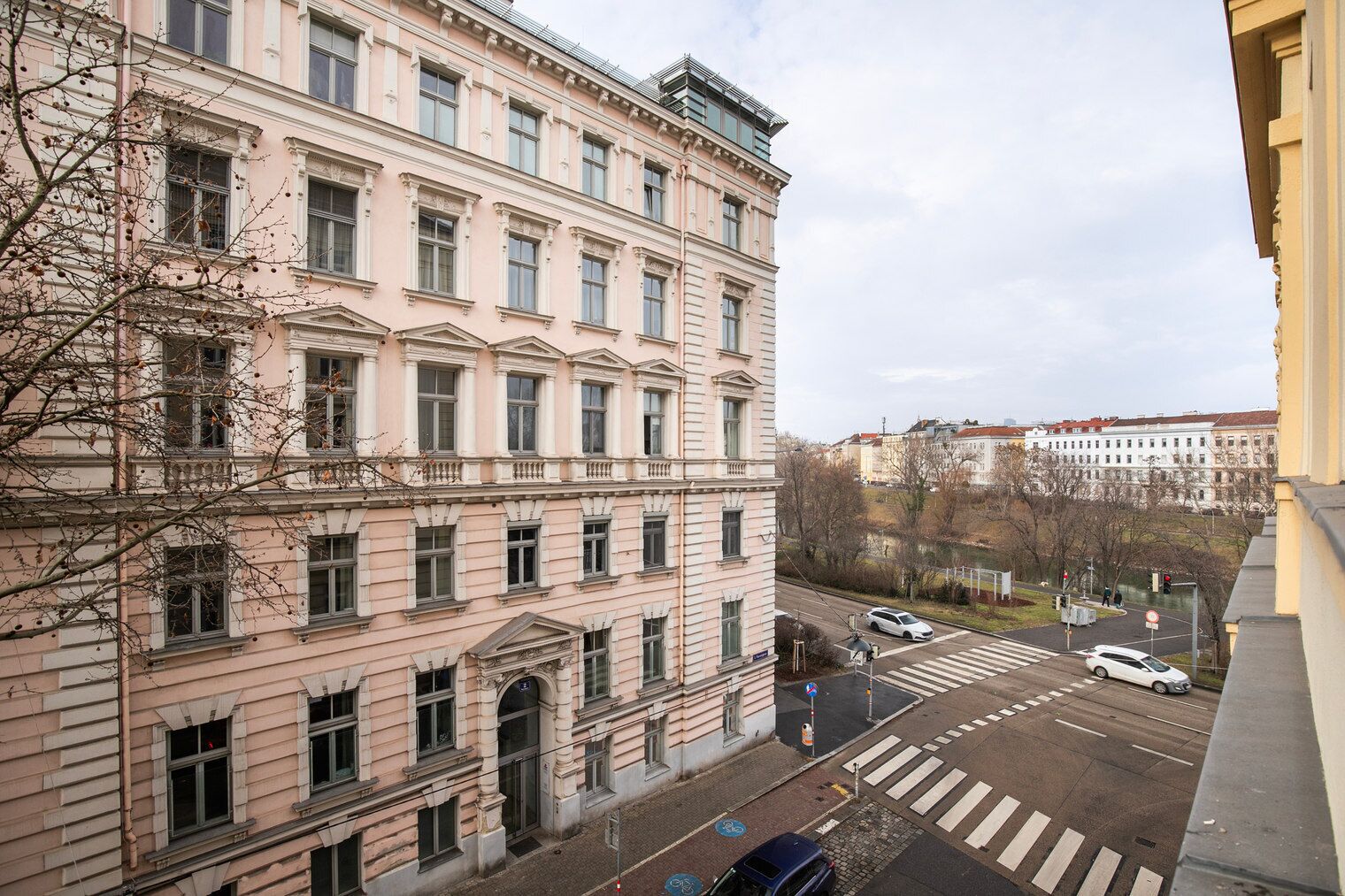 A multi-story building with a classical architectural style, featuring a central entrance with a large doorway and multiple windows on each floor.