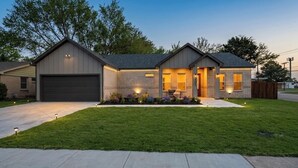 A modern two-story house with a garage, a well-maintained lawn, and outdoor lighting. - Luxe 4BR/3BA, 3 King Beds—Near AT&T, DFW, Dallas (Grand Prairie)
