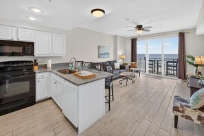 A modern kitchen with white cabinetry, a built-in oven, and a granite countertop. - Nana's Sweet Retreat at Ocean Walk (Daytona Beach)