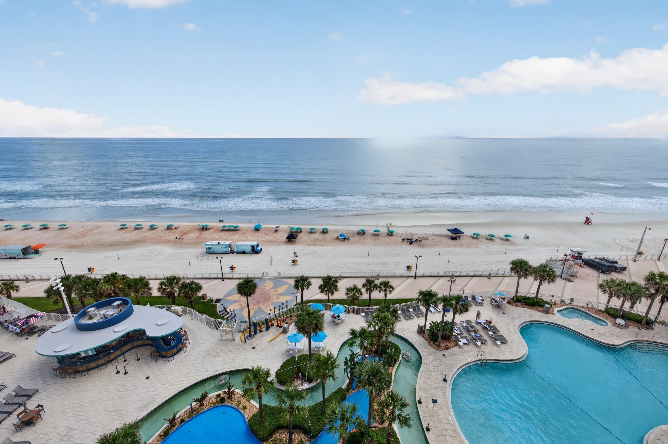 A resort with a beach, a pool area, and a lifeguard tower.