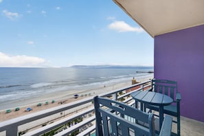 Ein Balkon mit Blick auf den Strand, einem Tisch und Stühlen.