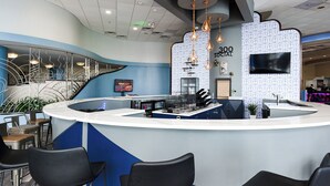 A modern reception area with a curved counter, black chairs, and a patterned wall. - Nana's Sweet Retreat at Ocean Walk (Daytona Beach)