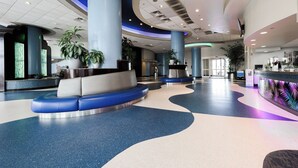 A spacious lobby with a curved seating area, large pillars, and potted plants. - Nana's Sweet Retreat at Ocean Walk (Daytona Beach)