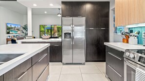 Eine moderne Küche mit einem Edelstahl-Kühlschrank, dunklen Holzschränken und einem eingebauten Ofen.
