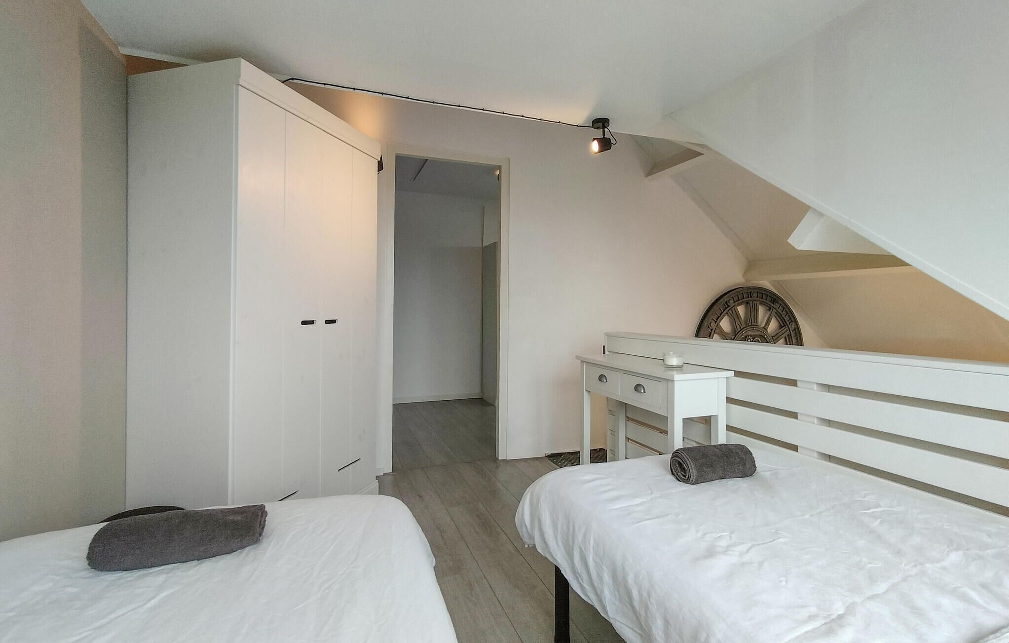 Un dormitorio con dos camas, un escritorio y una escalera.