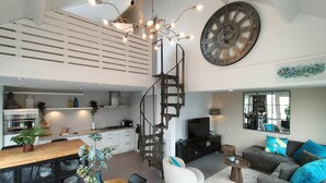 Un interior modern amb cuina, zona de menjador, saló i una escala espiraltra.