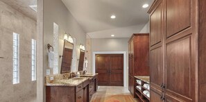 A bathroom with a marble vanity, double sinks, a large mirror, and wooden cabinetry. - NW Tuscan Retreat — 180° Vistas & Private Hot Tub (Harrison)
