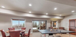 A room with a ping pong table, a dining table with chairs, and a fireplace. - NW Tuscan Retreat — 180° Vistas & Private Hot Tub (Harrison)