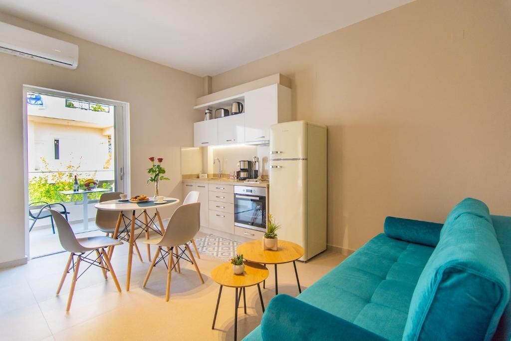 A modern kitchen with white cabinets, a refrigerator, and a dining area with a round table and chairs.