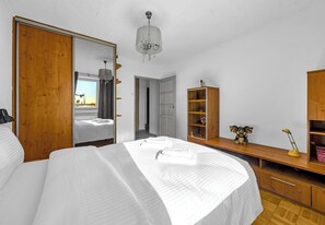 Een slaapkamer met een groot bed, een houten garderobe en een bureau met een lamp.
