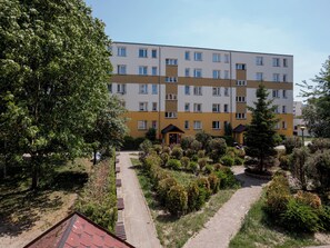 A multi-story residential building with a garden area in front, including pathways and greenery. - Toruń Urban Comfort Apartment (Toruń)