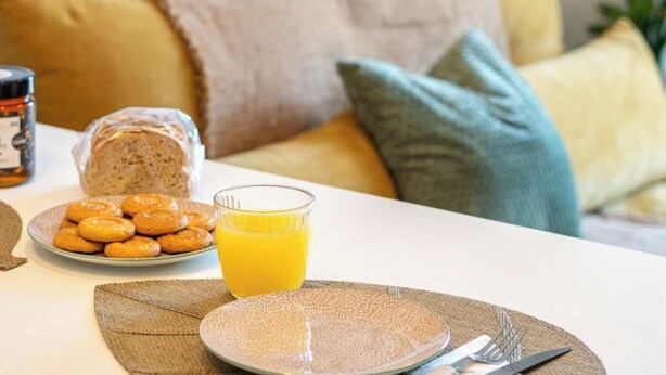 Een ontbijtje met een bord koekjes, een glas jus d'orange en een brood op een tafel.