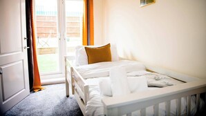 Un dormitorio con cama, ventana con cortinas, una puerta y un pequeño adorno en la pared.