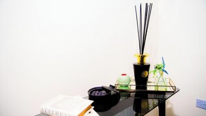 Una mesa de cristal negro con un libro, un jarrón negro con tapa roja y un recipiente de vidrio con tapa verde.