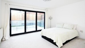 A bedroom with a large sliding glass door leading to a balcony. - 8 Bedroom House Sleeps 20 - Private Garden (Wolverhampton)