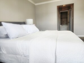 Un lit bien fait, avec du linge de lit blanc, dans une chambre d’hôtel.