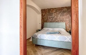 A bedroom with a bed, a nightstand, and a stone-patterned wall.