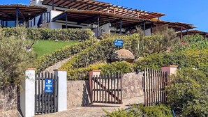A modern villa with a stone facade, a covered patio, and a gated entrance.