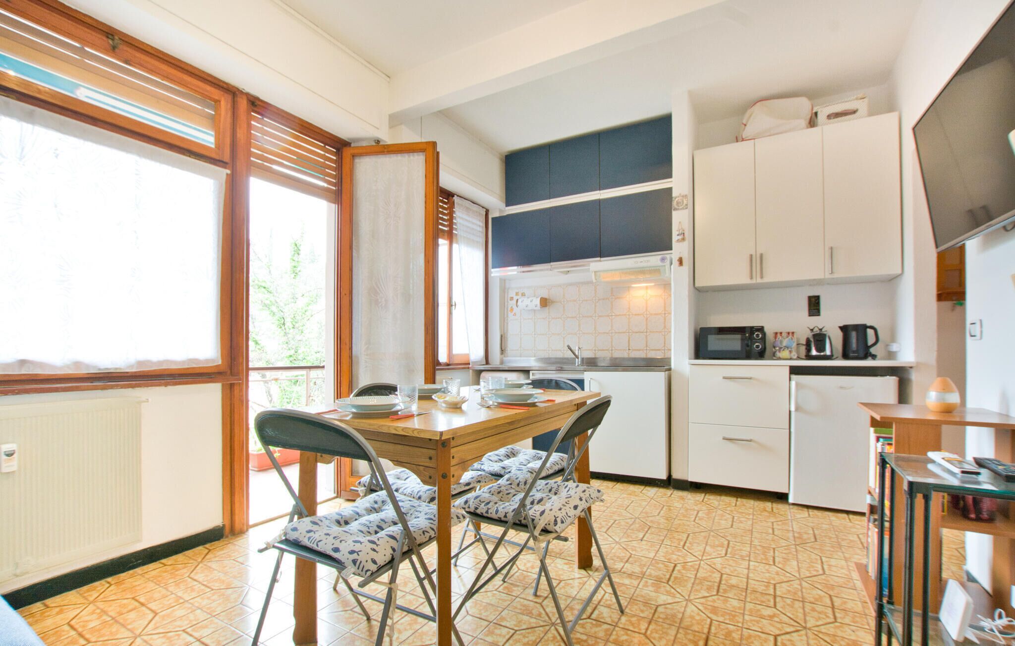Une cuisine compacte avec un coin repas, comprenant une table et des chaises pliantes, un four à micro-ondes et des placards blancs.
