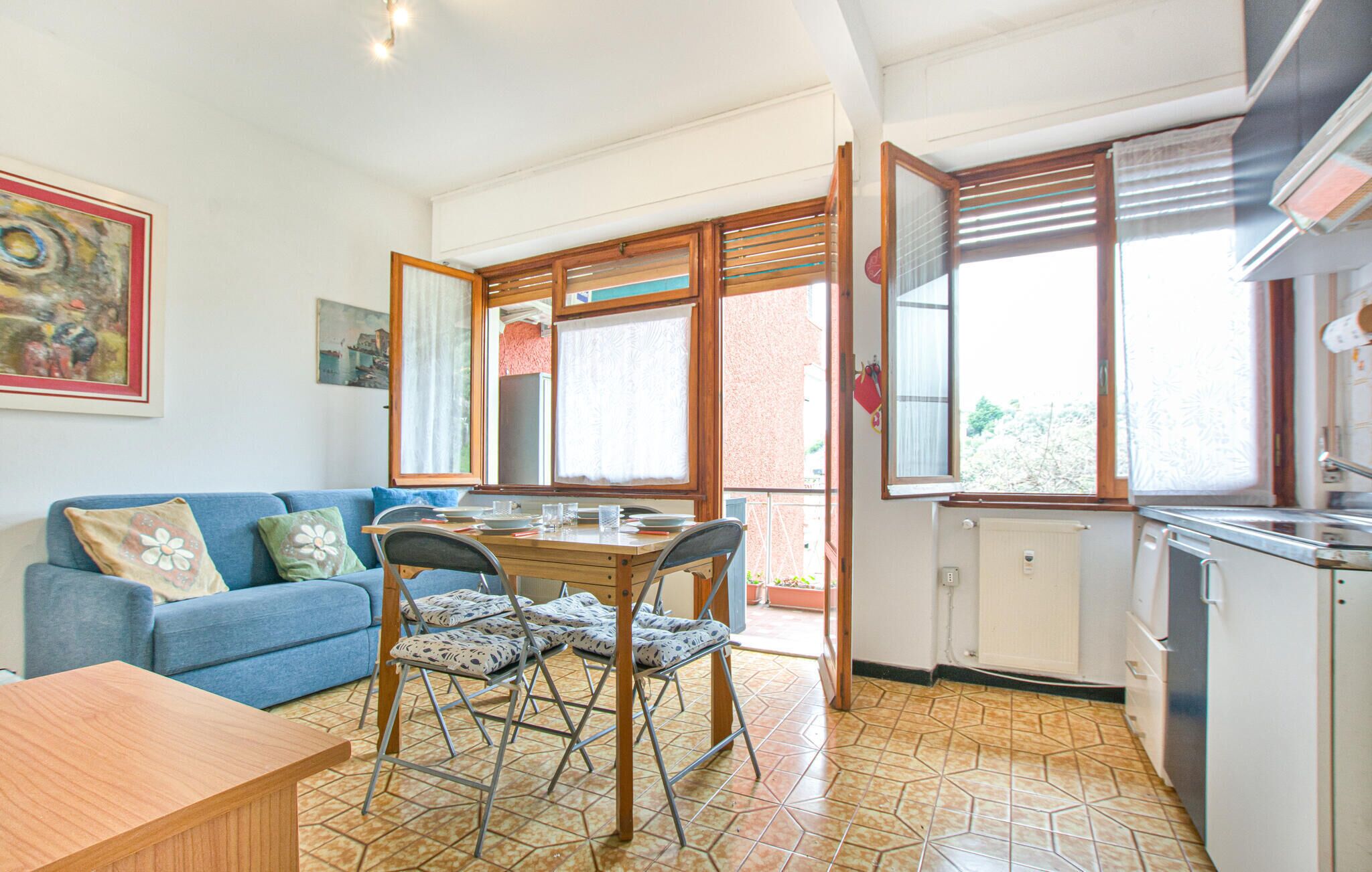 A cozy living room with a blue sofa, a wooden dining table, and patterned chairs.