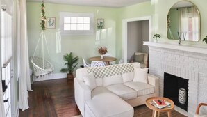 A living room with a white sofa, a checkered throw, a fireplace, and a hanging chair. - Relaxing 3-bedroom house in terrific Cincinnati with Firepit and Patio (Cincinnati)