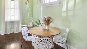 A dining area with a round wooden table, white wicker chairs, and a hanging floral arrangement. - Relaxing 3-bedroom house in terrific Cincinnati with Firepit and Patio (Cincinnati)