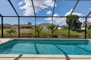 A swimming pool with a view of houses and a body of water. - Sunset Retreat with heated pool (Rotonda West)