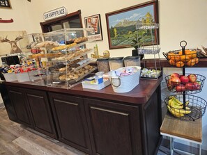 A buffet counter with various food items, a sign reading 'OUR HAPPY PLACE,' and a painting of a mountain landscape.