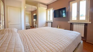 Un dormitorio con una cama grande, un televisor montado en la pared y un ventanal con vistas.