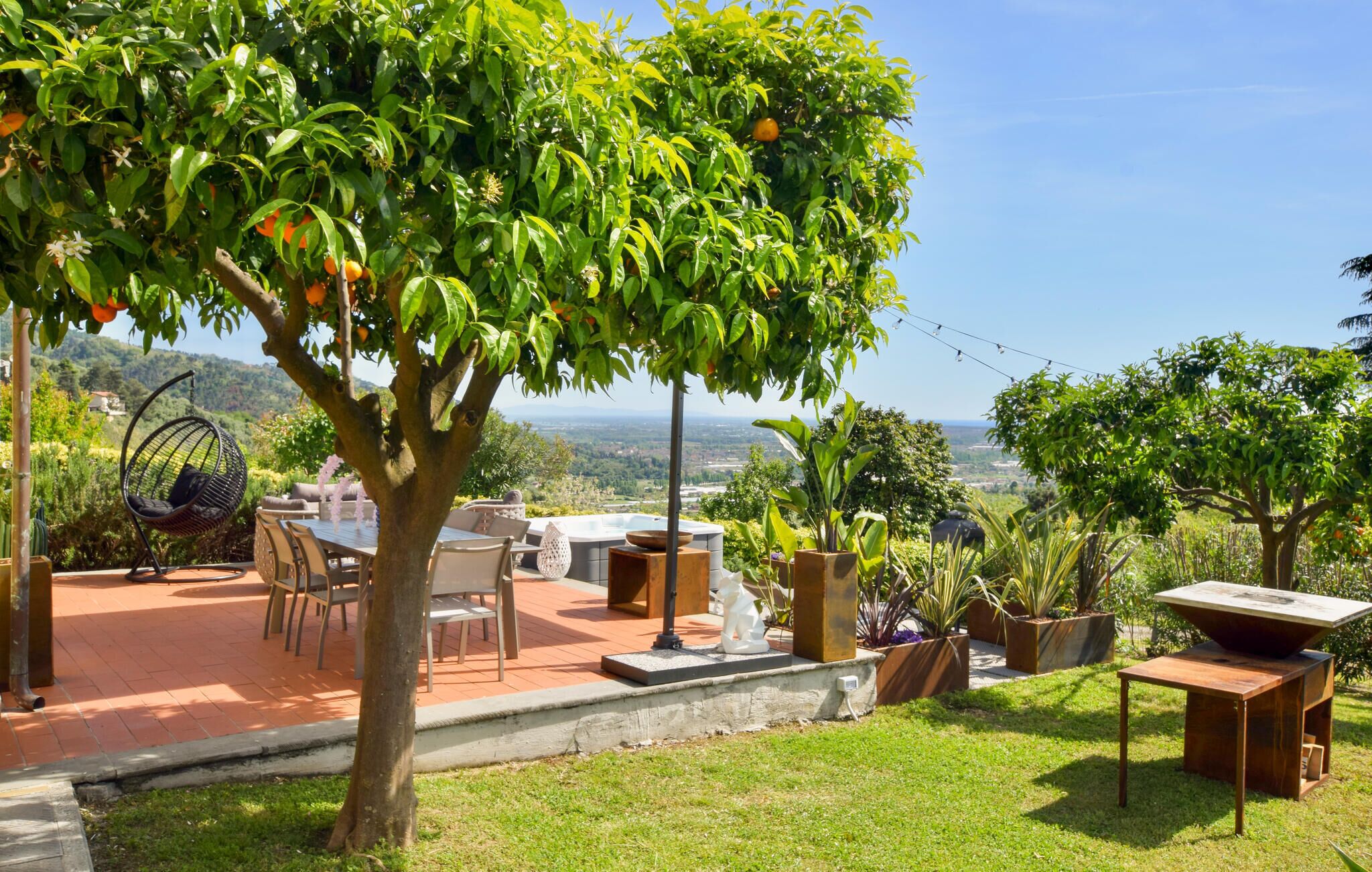 Un patio con mobiliario exterior, una silla colgante y vistas del paisaje.
