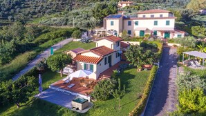 Una casa de dos pisos con un patio, un jacuzzi y un jardín.
