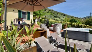 Un patio con mobiliario exterior, una bañera de hidromasaje y vistas a una colina.
